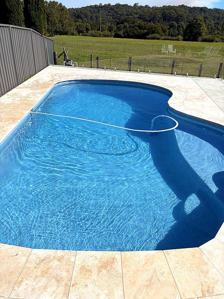 Kidney pool with travertine surrounds and a rural view