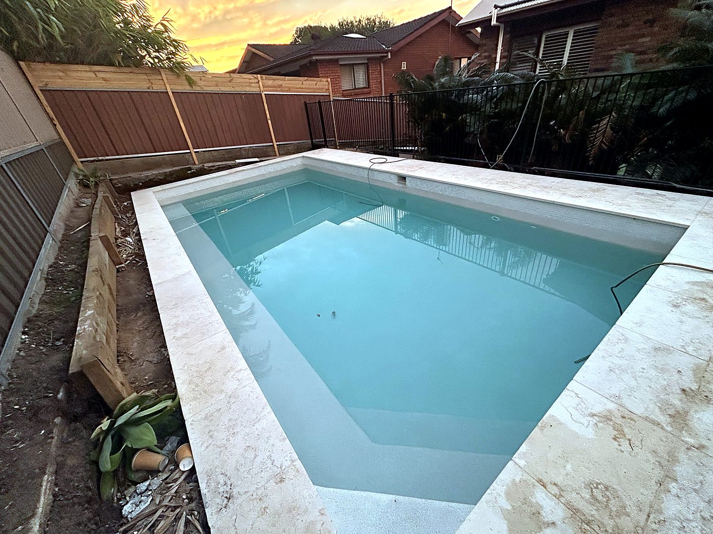 New pool interior at sunset with travertine coping